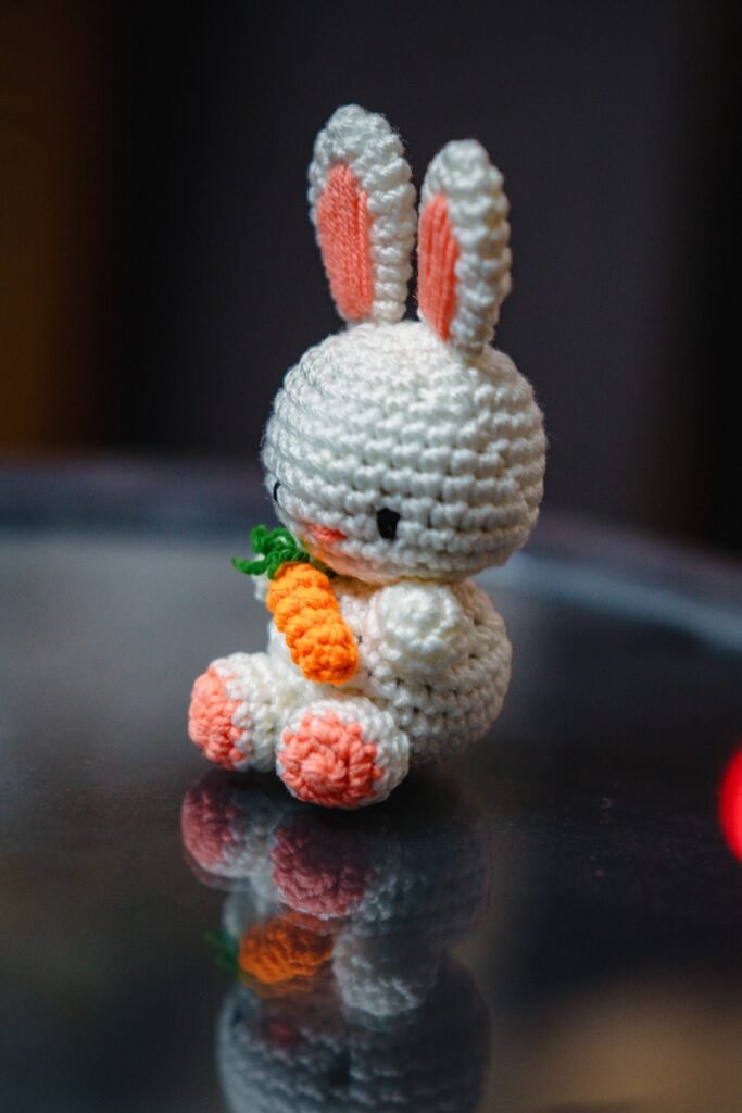 A cute crocheted bunny holding a carrot.